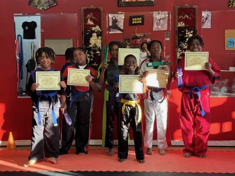 Students displaying certificates and new belts