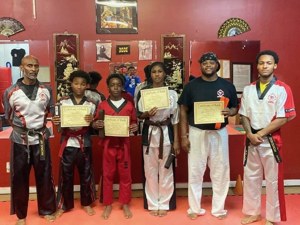 Students and instructors celebrating belt advancement at Alpha & Omega